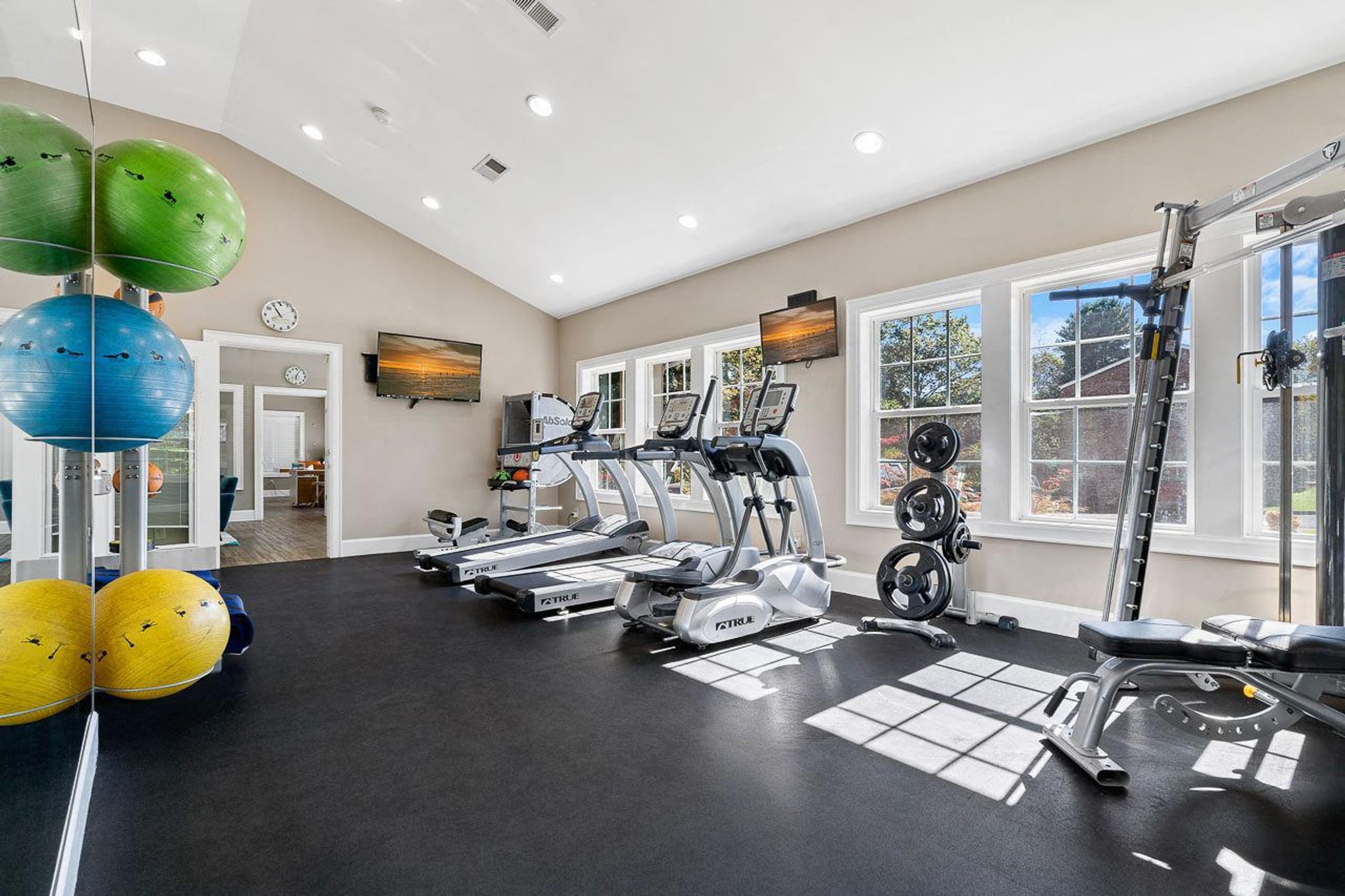 A spacious home gym with various exercise equipment and a large window.
