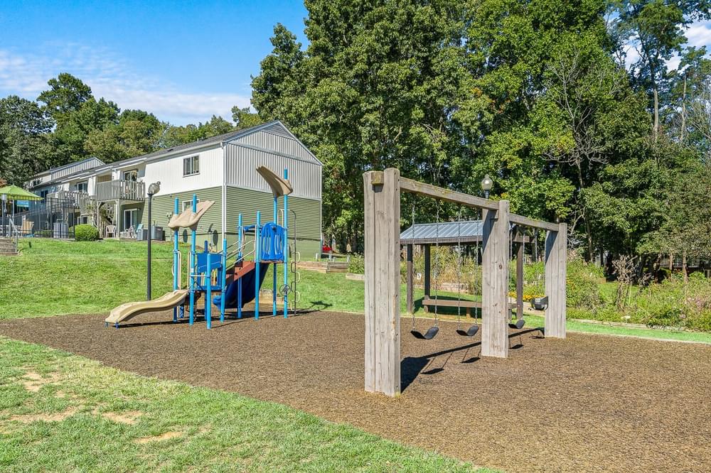 a playground with a swing set in front of a house