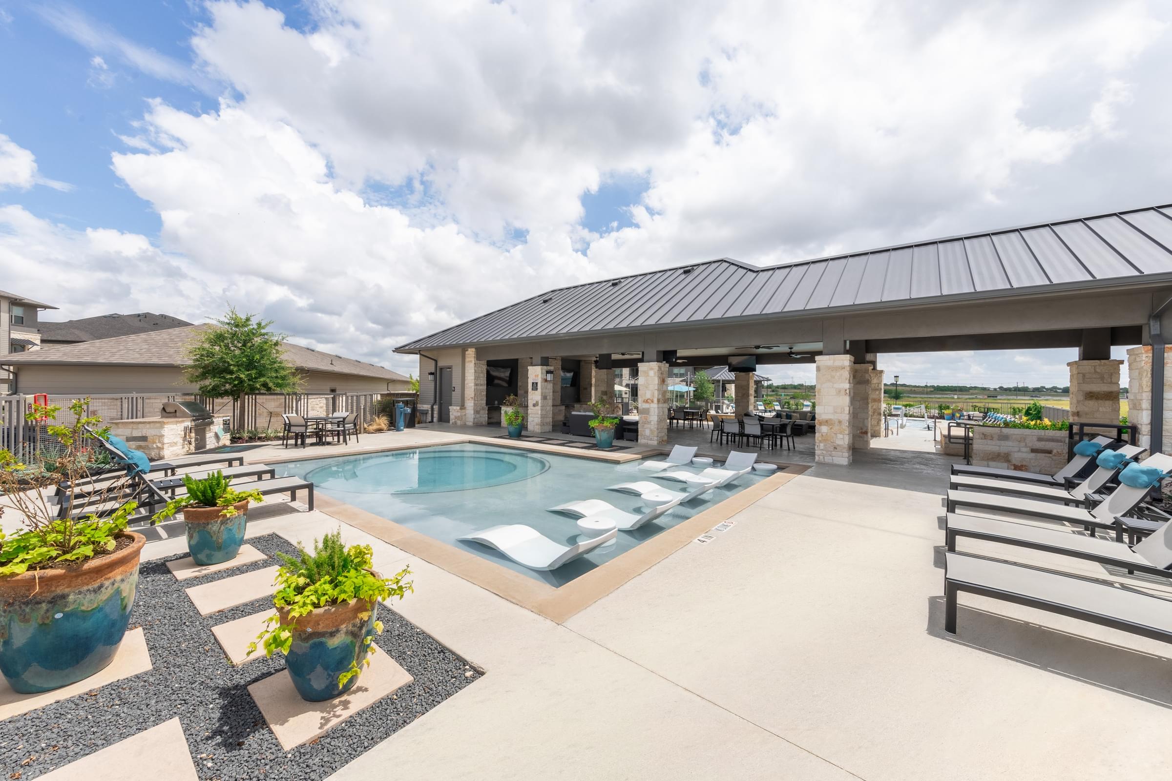 the enclave apartments pool area with lounge chairs and tables and a pool