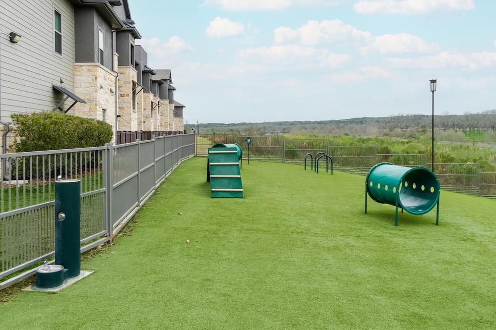 a playground on the side of a house with a green field and a fence