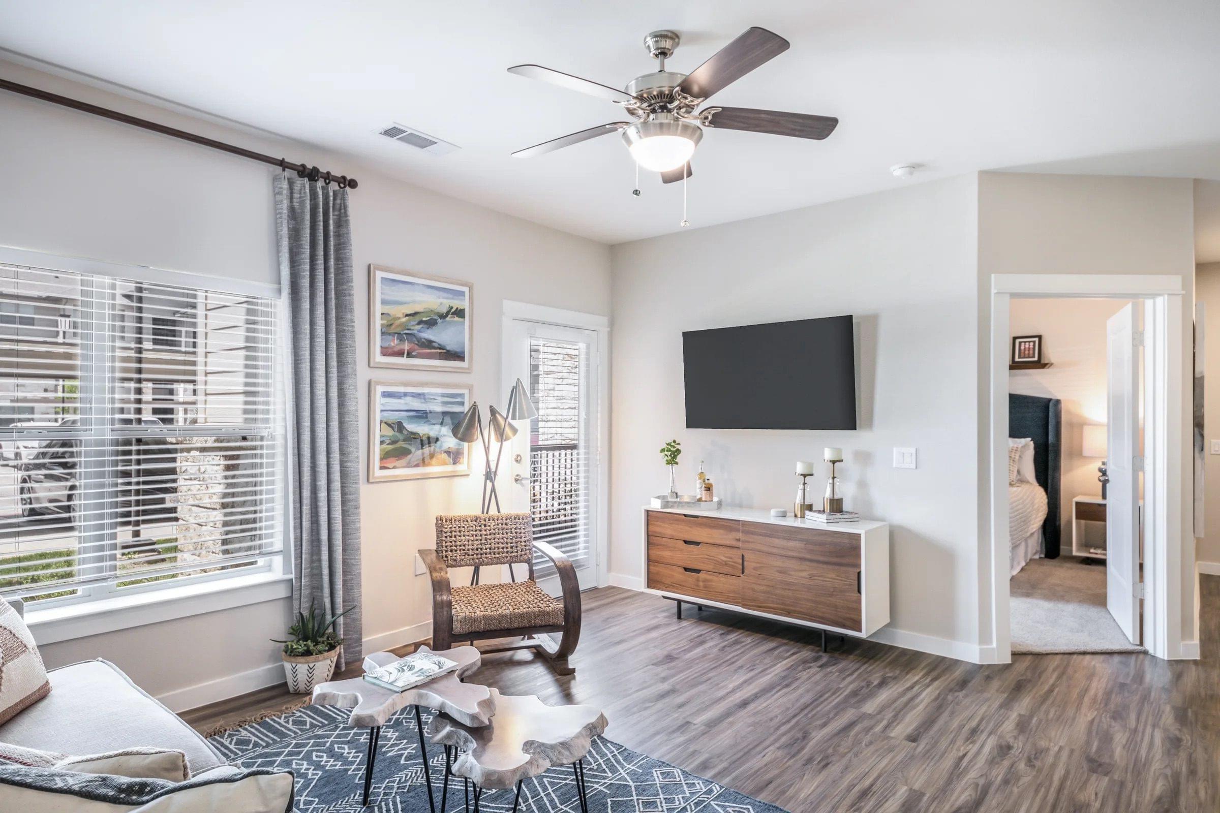A living room with a ceiling fan and a flat screen TV.