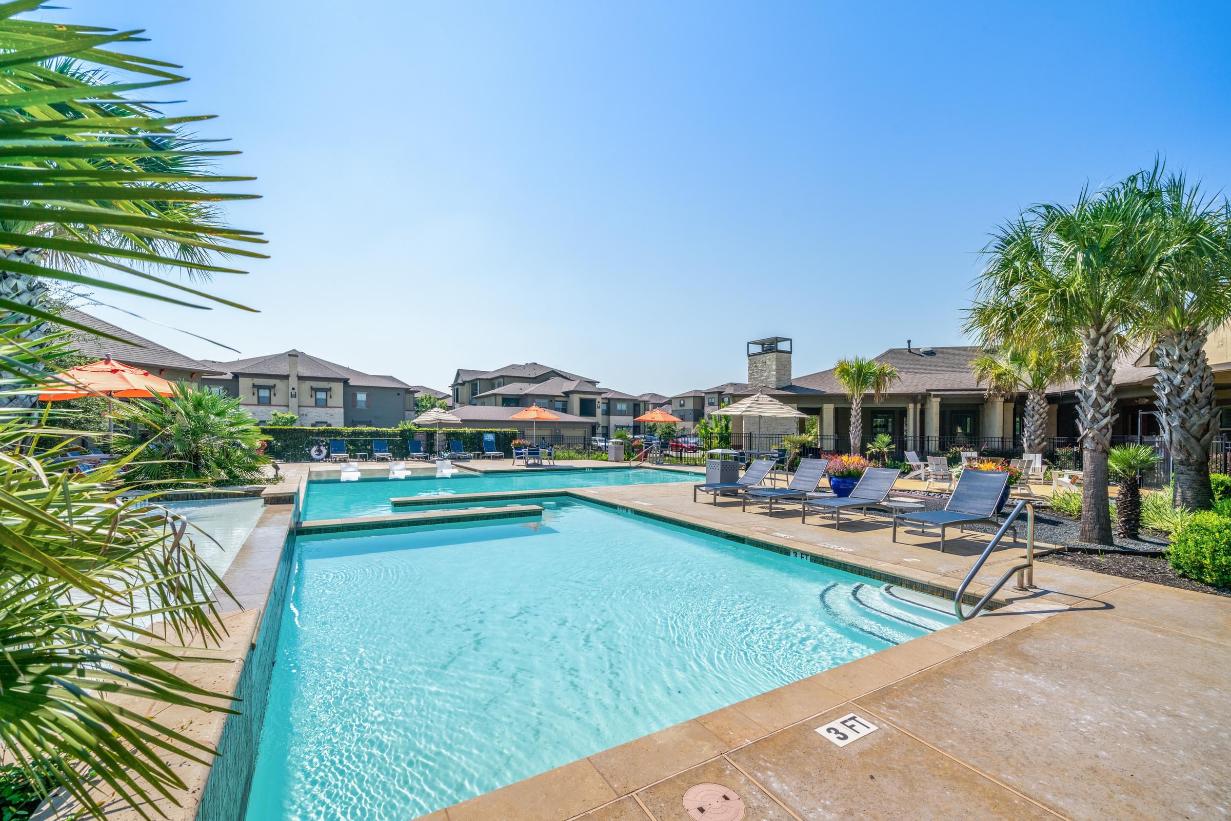 a swimming pool with chairs and umbrellas at the resort on a sunny day