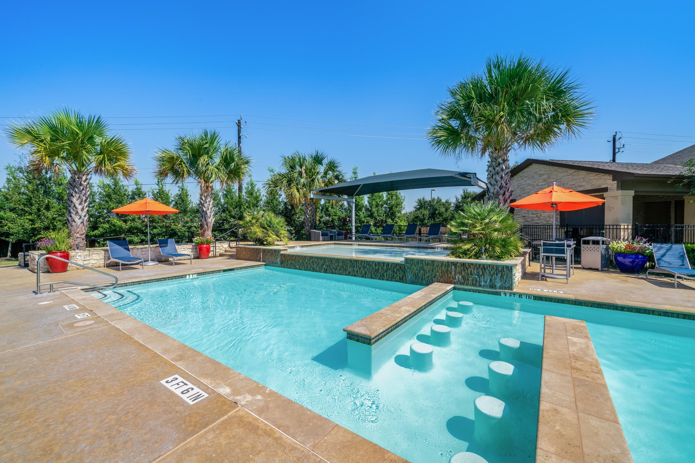 a swimming pool with palm trees and umbrellas in front of a house