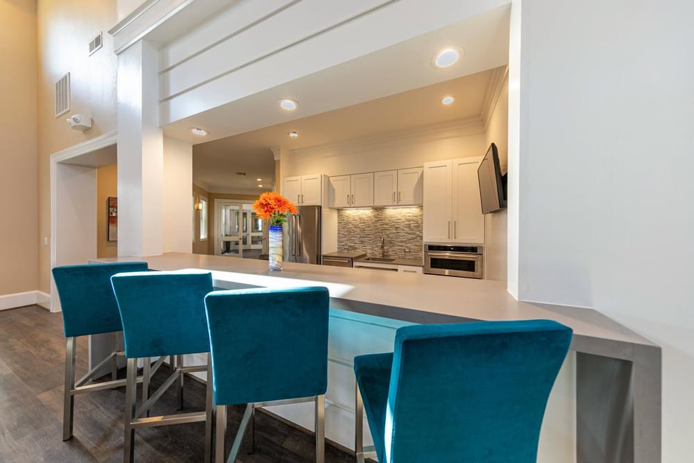 a kitchen with a long counter with blue chairs