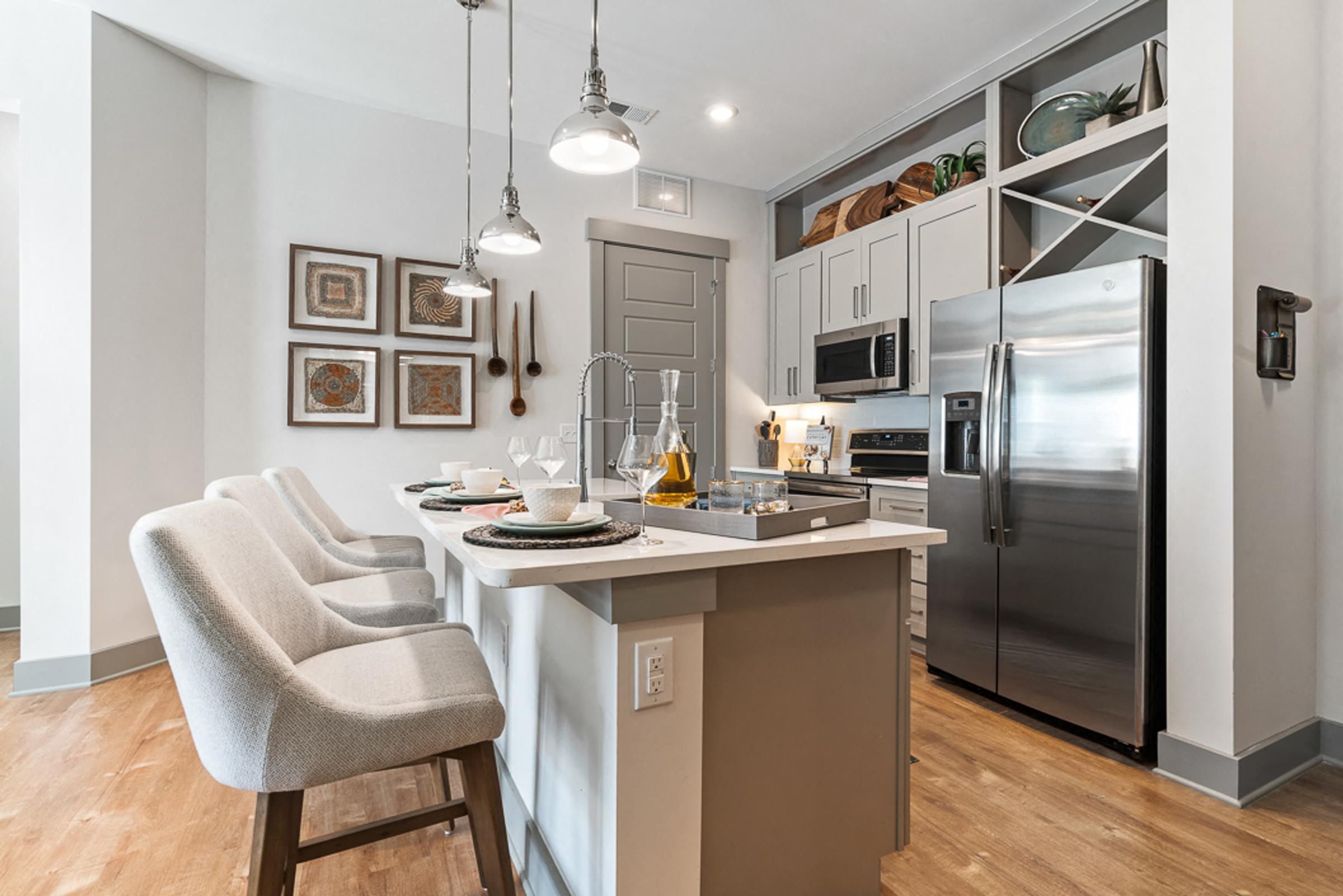 Kitchen island breakfast bar with designer chairs and stainless steel appliances