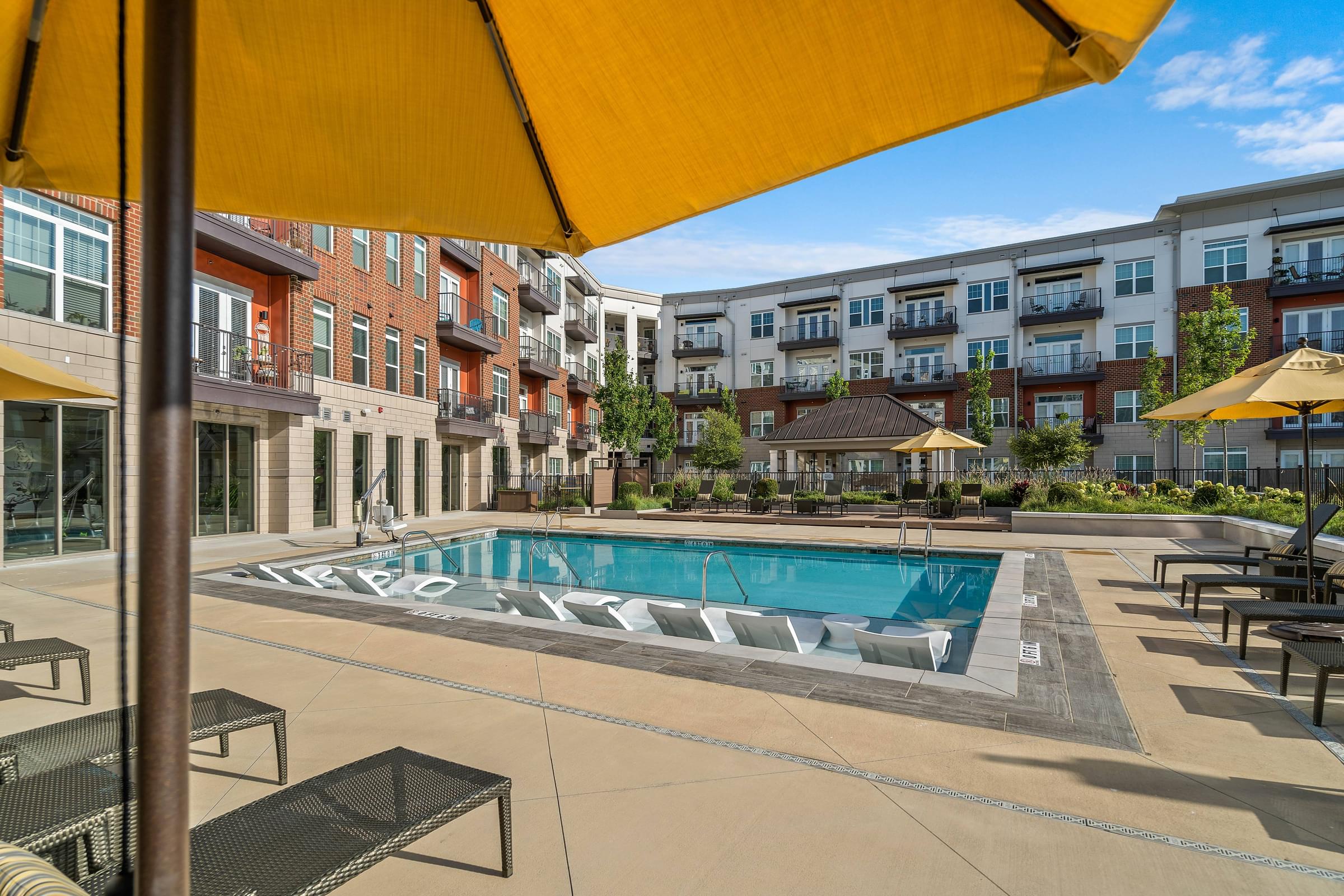 a swimming pool with umbrellas in front of an apartment building