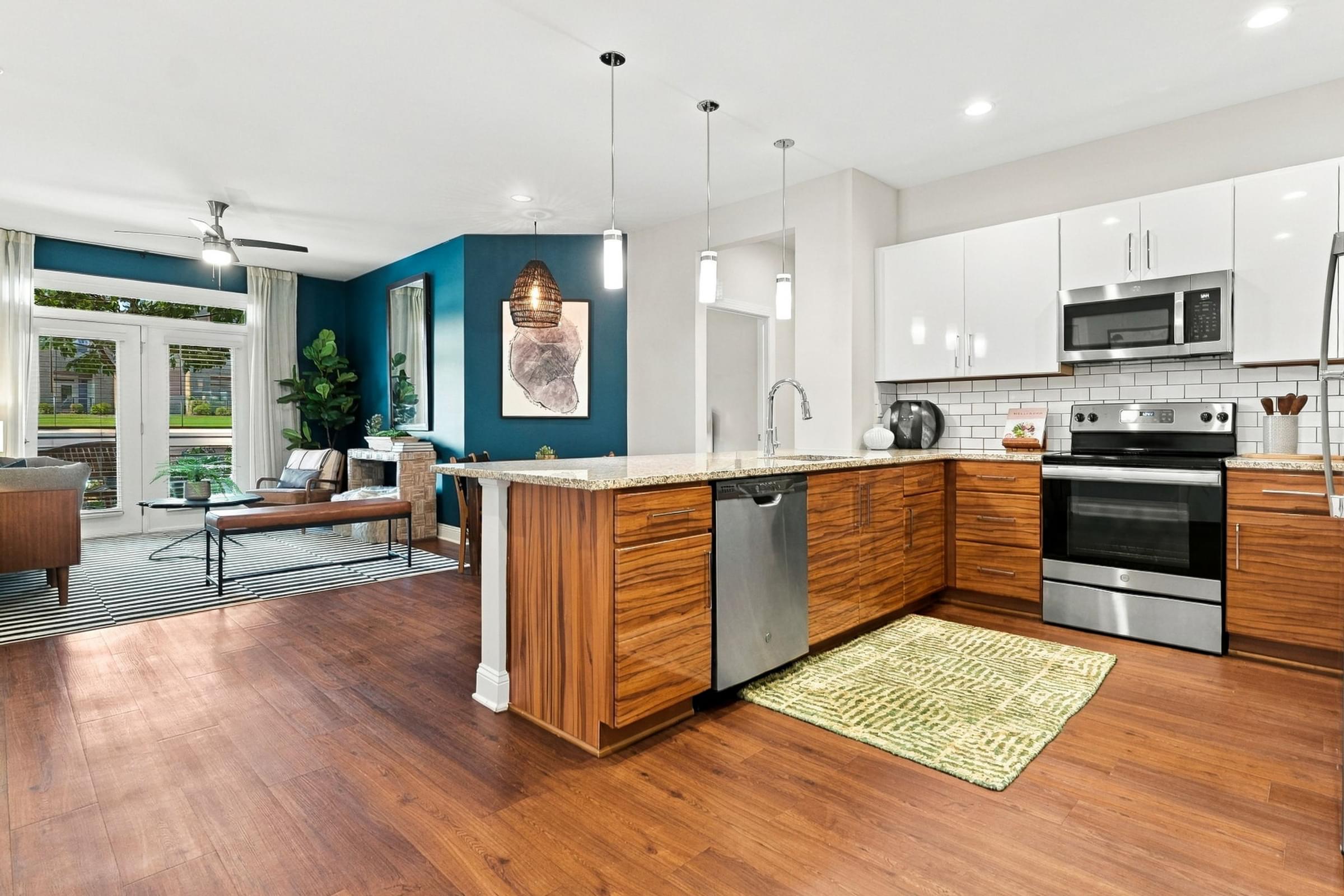 A modern kitchen with wooden floors and stainless steel appliances.
