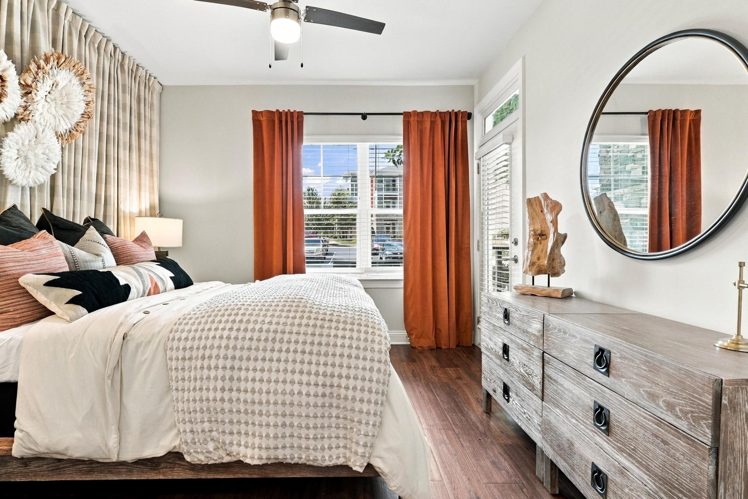 A bedroom with a large bed, a dresser, and a ceiling fan.