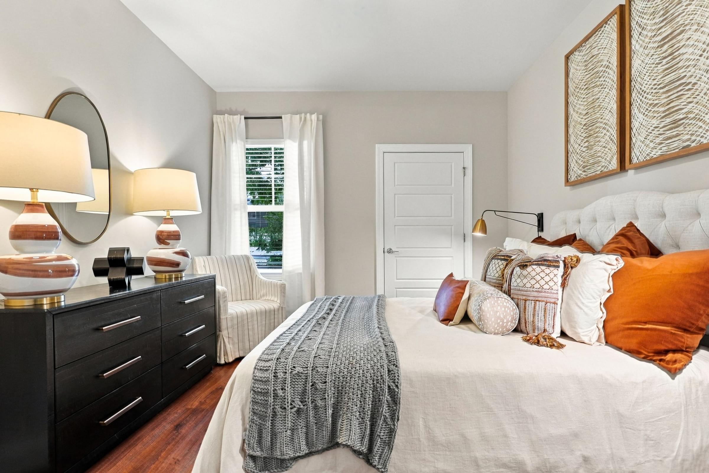 A bedroom with a white bed and a grey blanket.