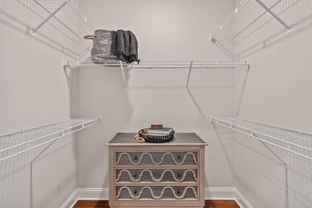 a walk in closet with two shelves and a dresser