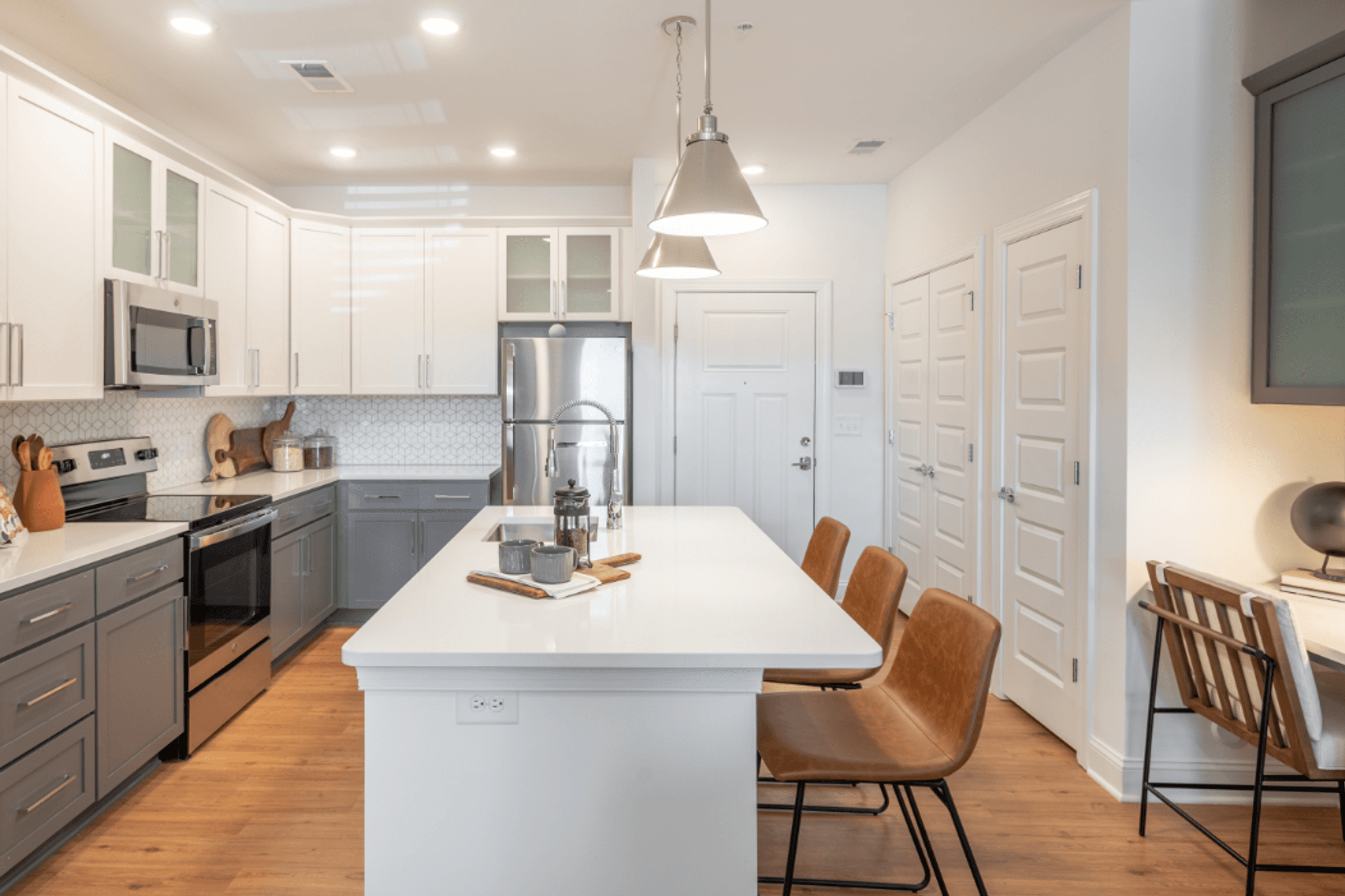 an open kitchen with a white counter top and a white island with chairs