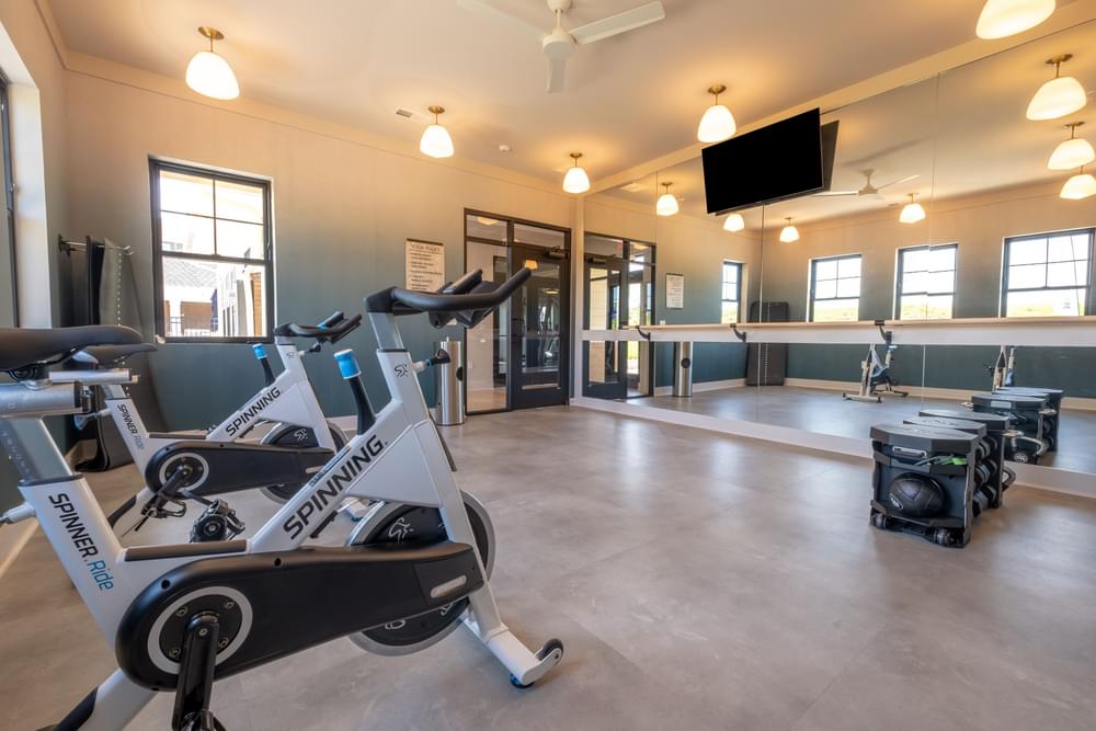 a gym with exercise equipment and a tv in the ceiling