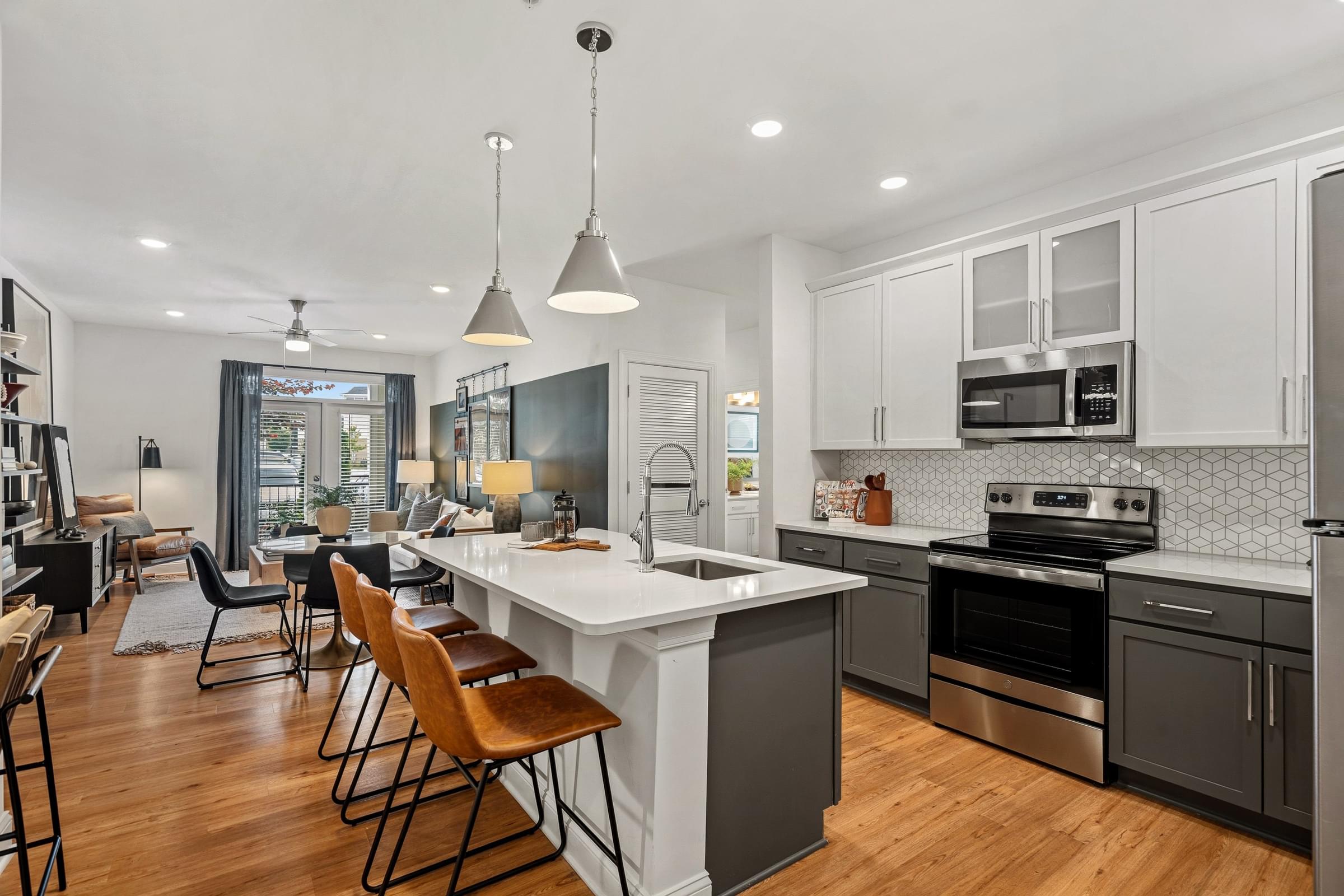 A modern kitchen with a white island and wooden floors.