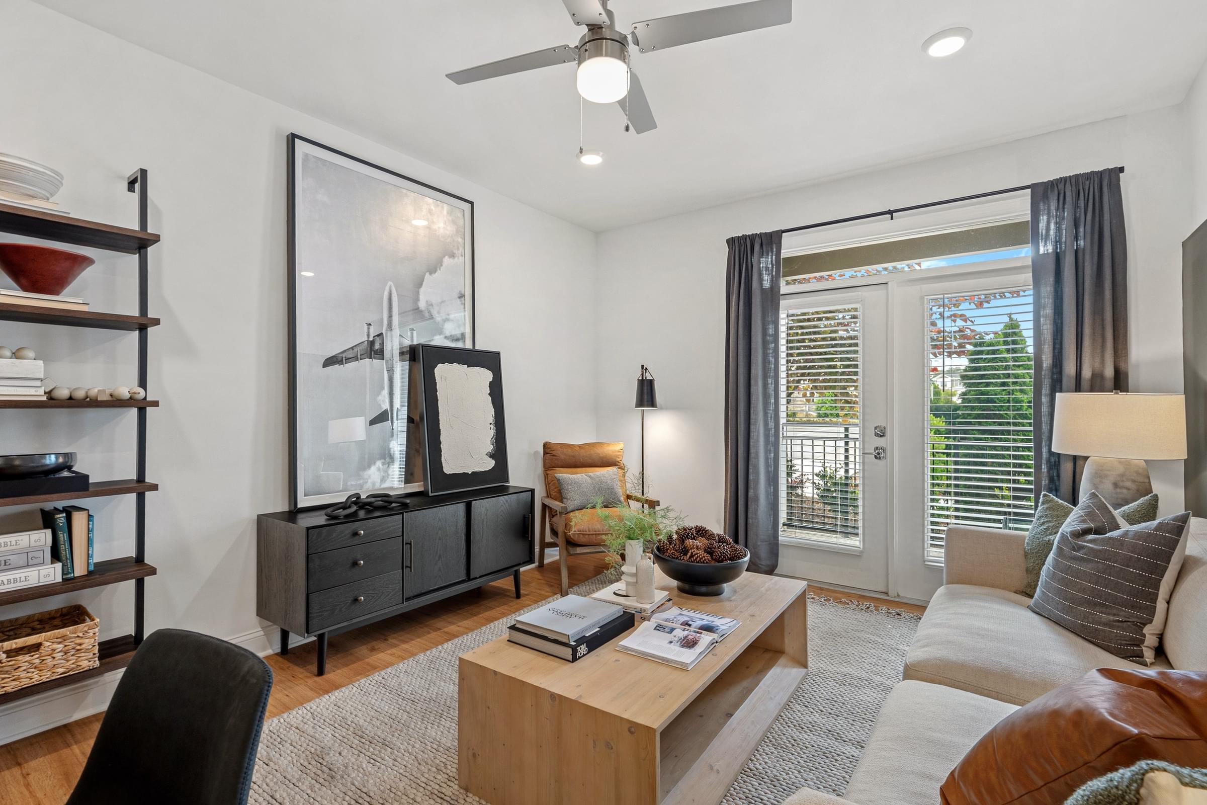 A modern living room with a black chair, a wooden coffee table, and a large mirror on the wall.