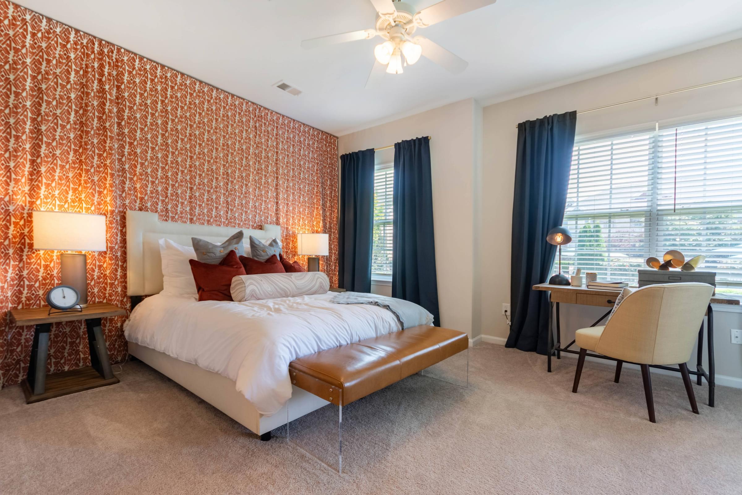 A bedroom with a bed, chair, and a ceiling fan.