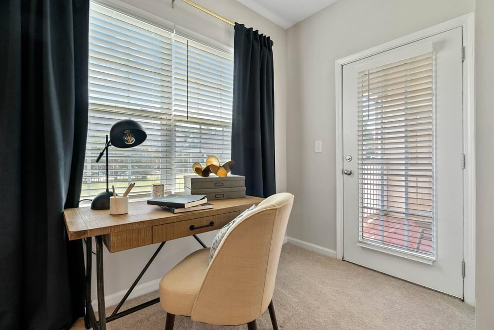 a home office with a desk and a window with blinds