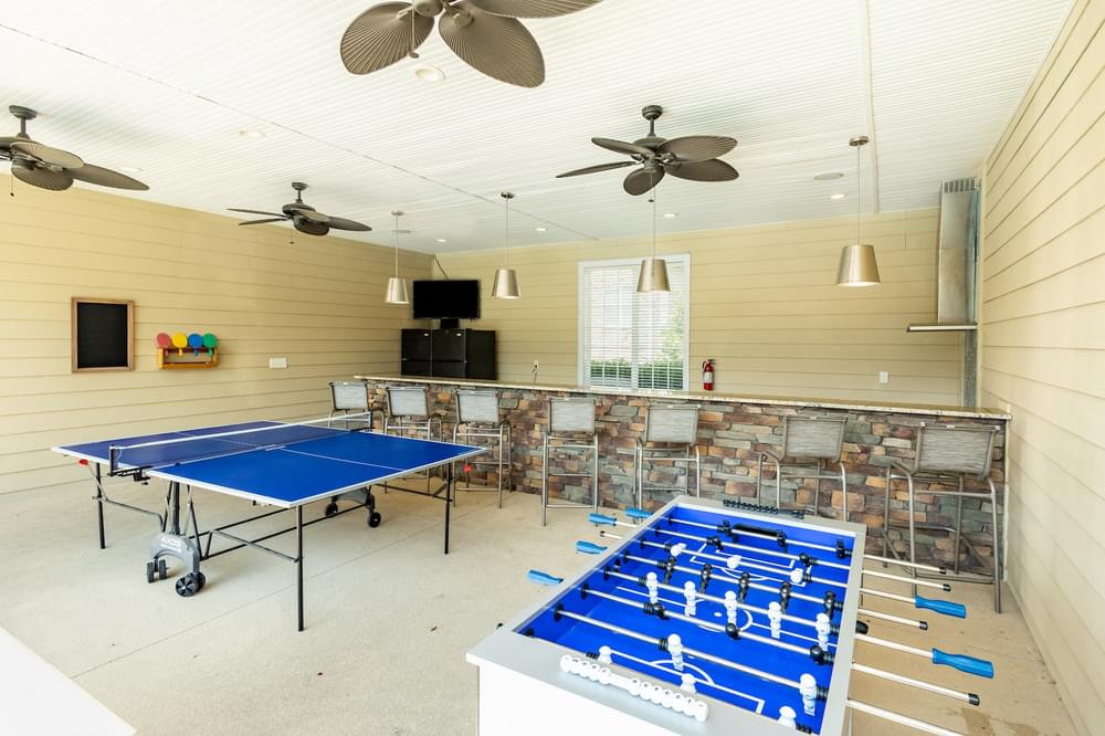 a game room with two ping pong tables and a bar