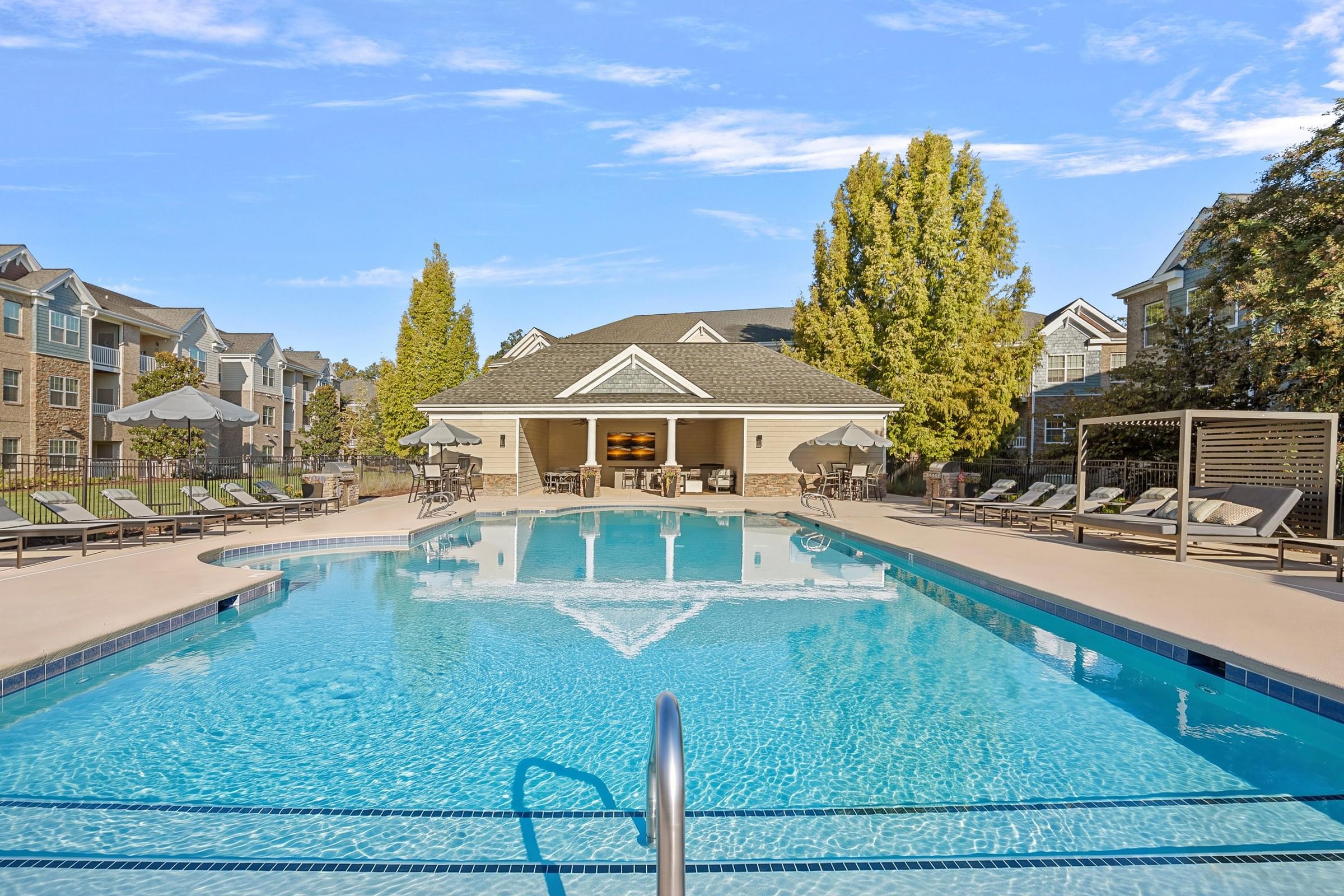 A large swimming pool in front of a building with a poolside lounge.