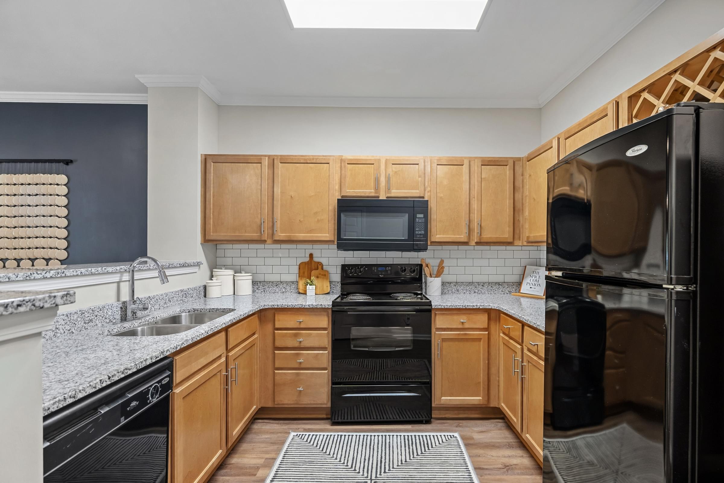 A kitchen with black appliances and wooden cabinets.