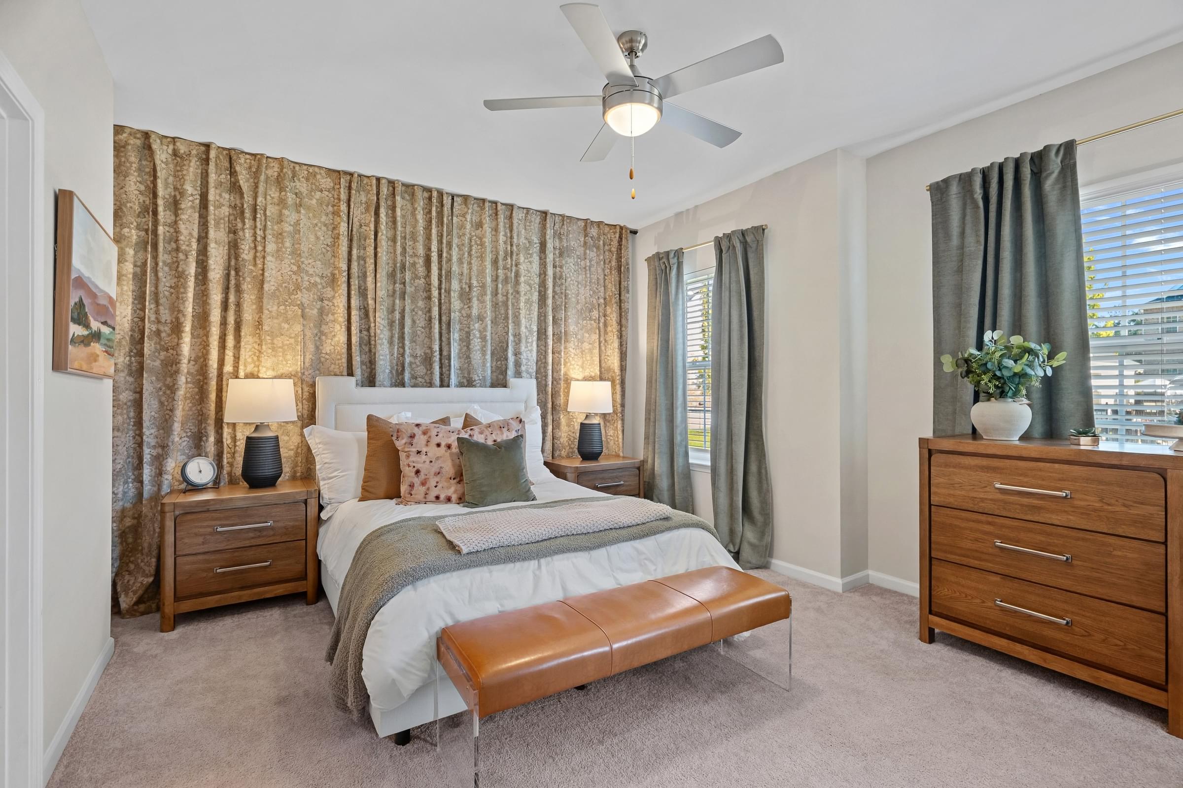 A bedroom with a bed, nightstands, and a ceiling fan.
