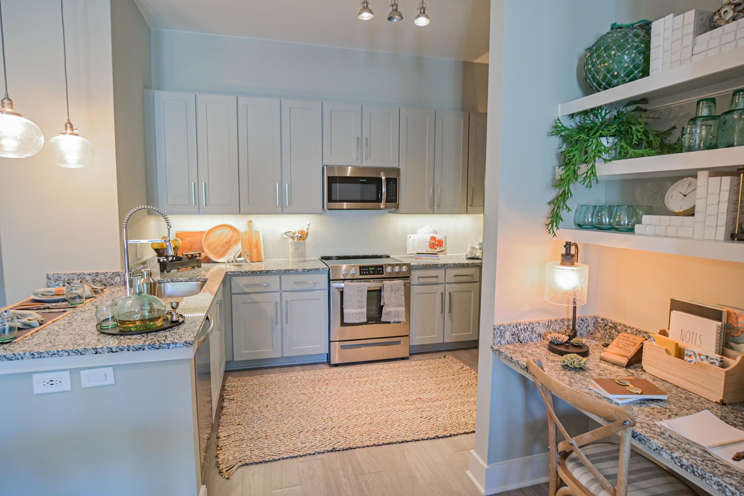 A kitchen with a refrigerator, microwave, oven, and sink.