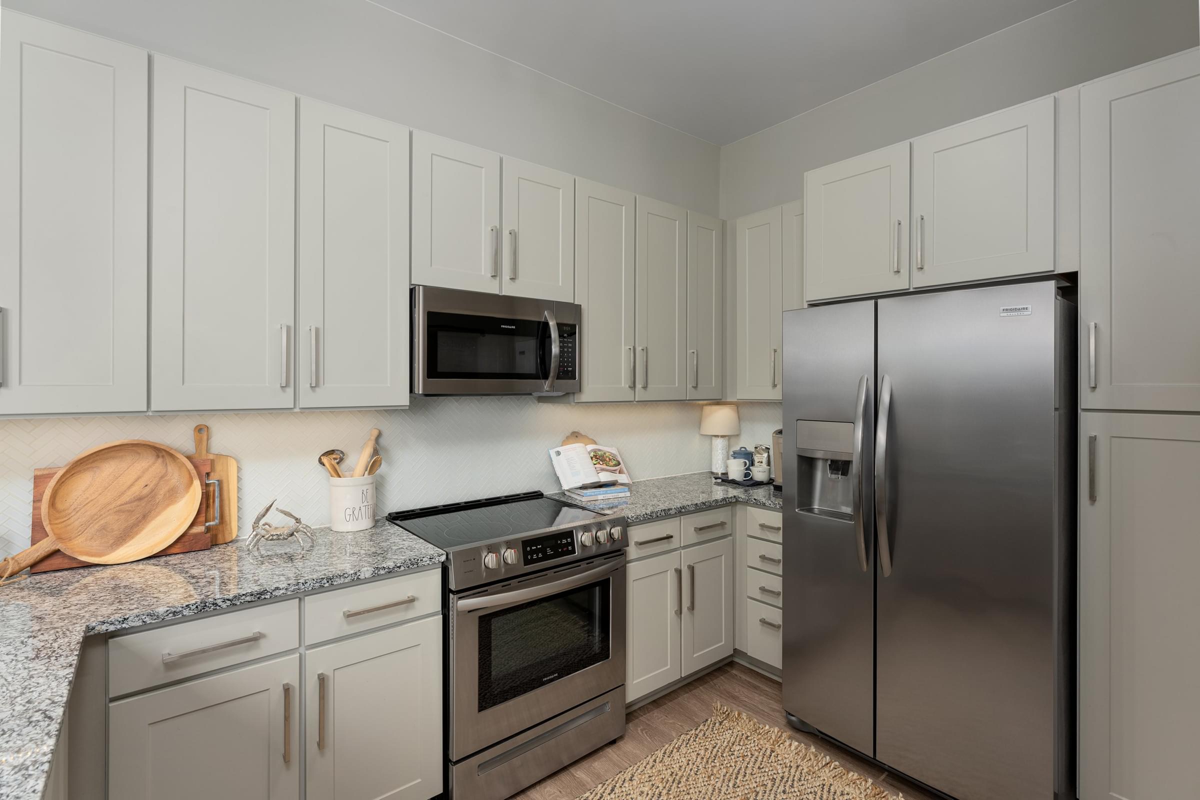 A kitchen with a refrigerator, oven, and microwave.