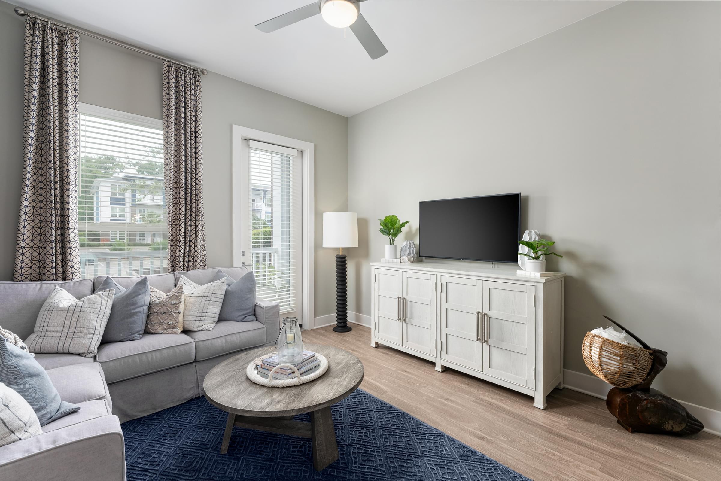 A living room with a grey sofa, a wooden coffee table, a white cabinet, and a flat screen TV.
