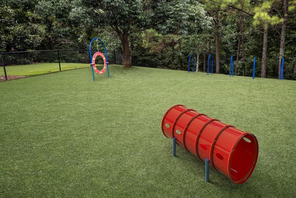 a playground with a swing set and red barrels on the grass