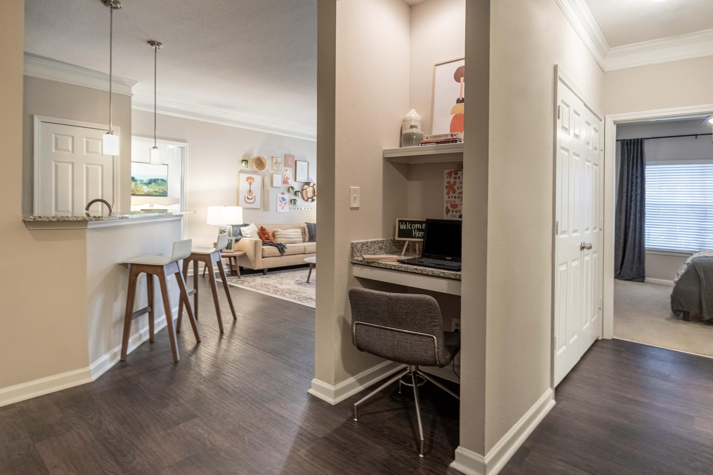 a kitchen and living room with a desk and a bar with stools