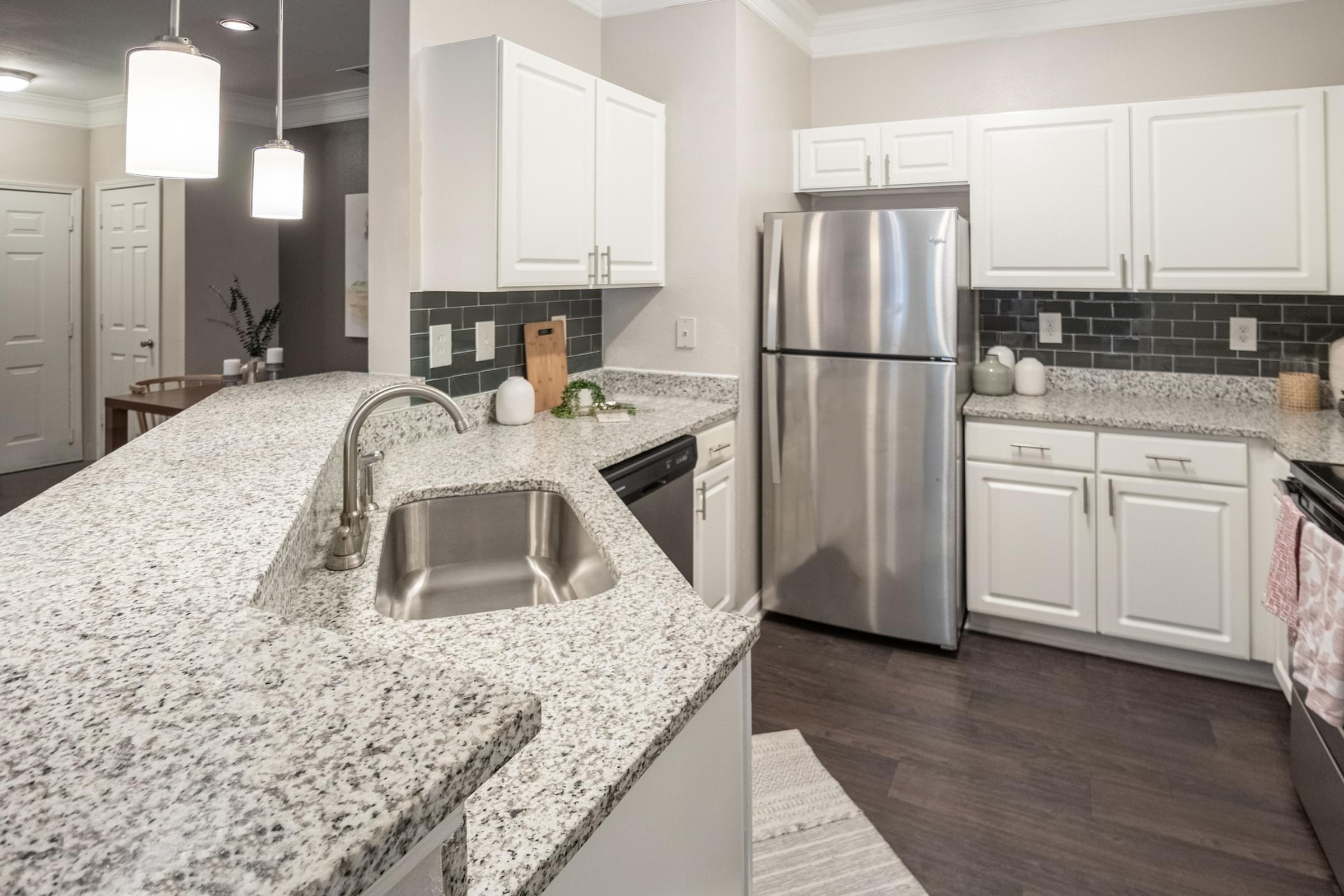 a kitchen with granite counter tops and a stainless steel refrigerator