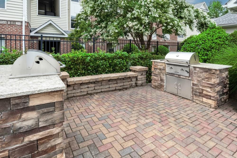 a brick patio with an outdoor kitchen and a grill