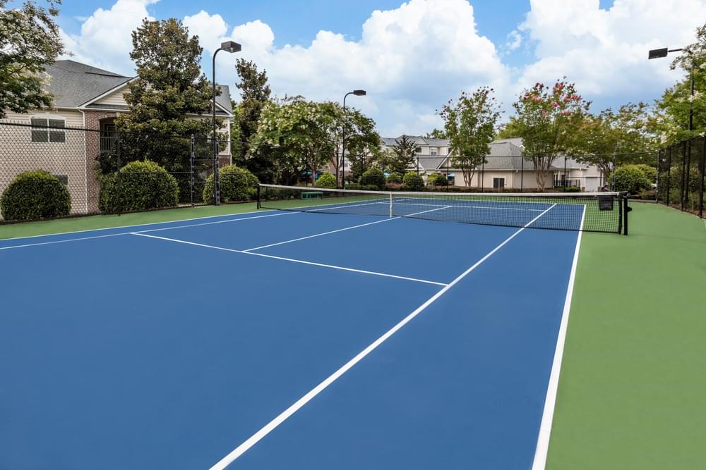 a blue and green tennis court in front of a house