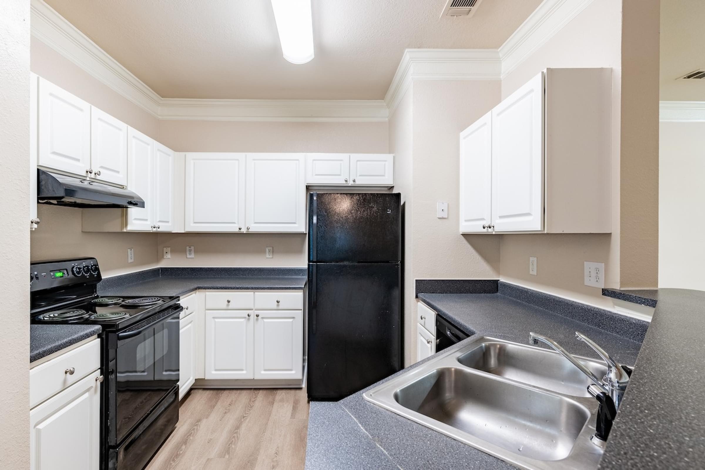 an empty kitchen with black appliances and white cabinets