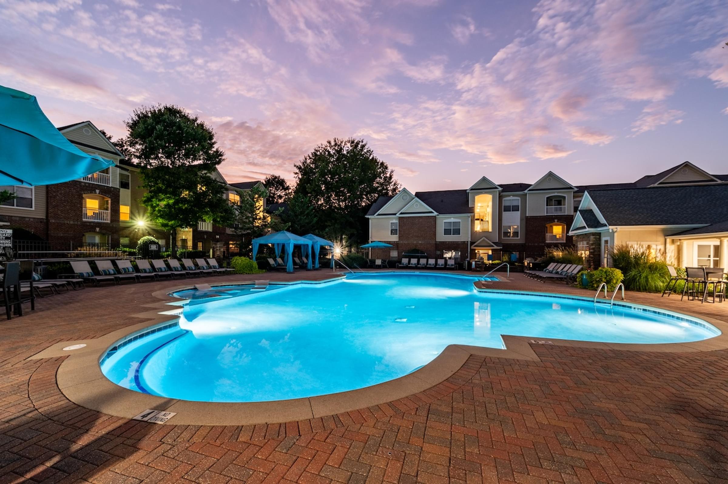 a large swimming pool at night with apartments in the background