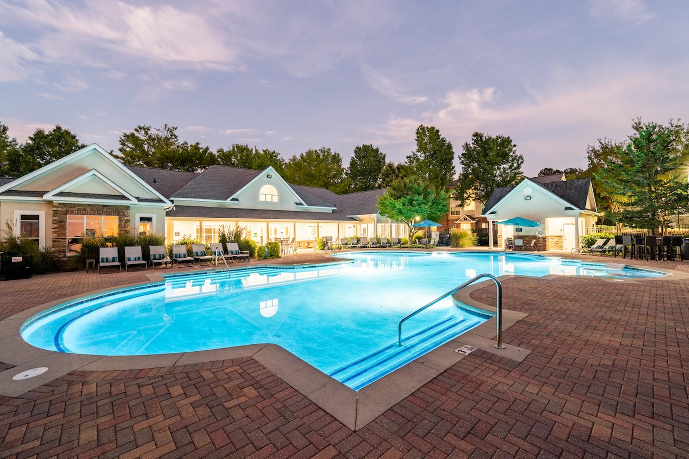 a swimming pool at night with apartments in the background