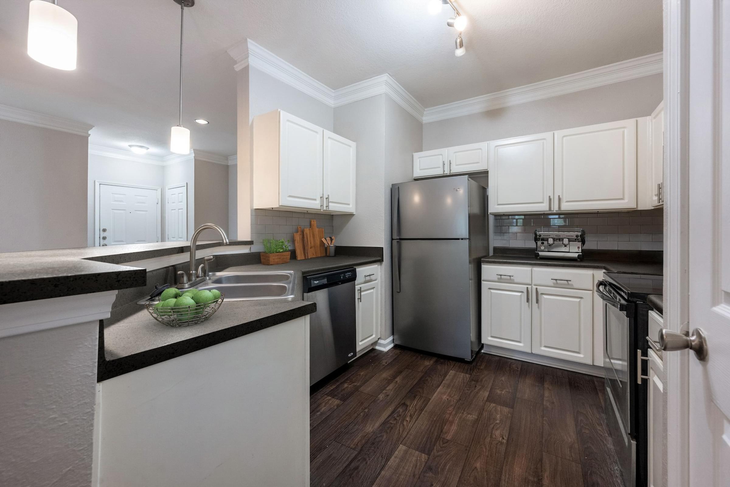 A kitchen with white cabinets and a black countertop.