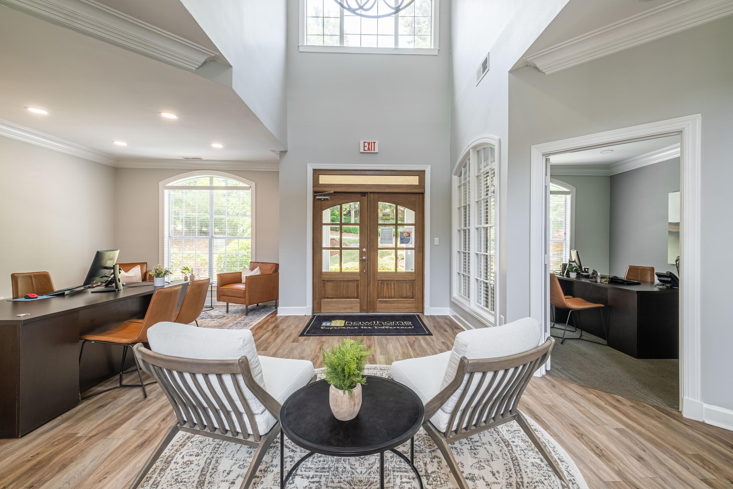 a living room with white chairs and a table and a wooden door