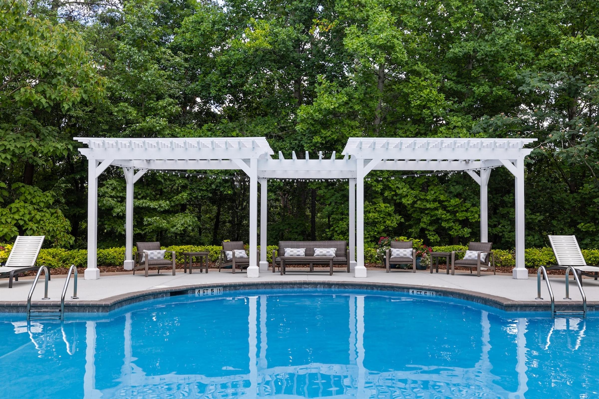 the pool and pergolas are next to a swimming pool