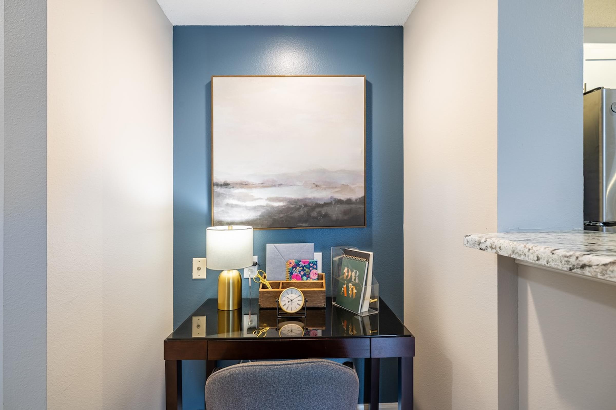 a desk with a chair and a painting on the wall