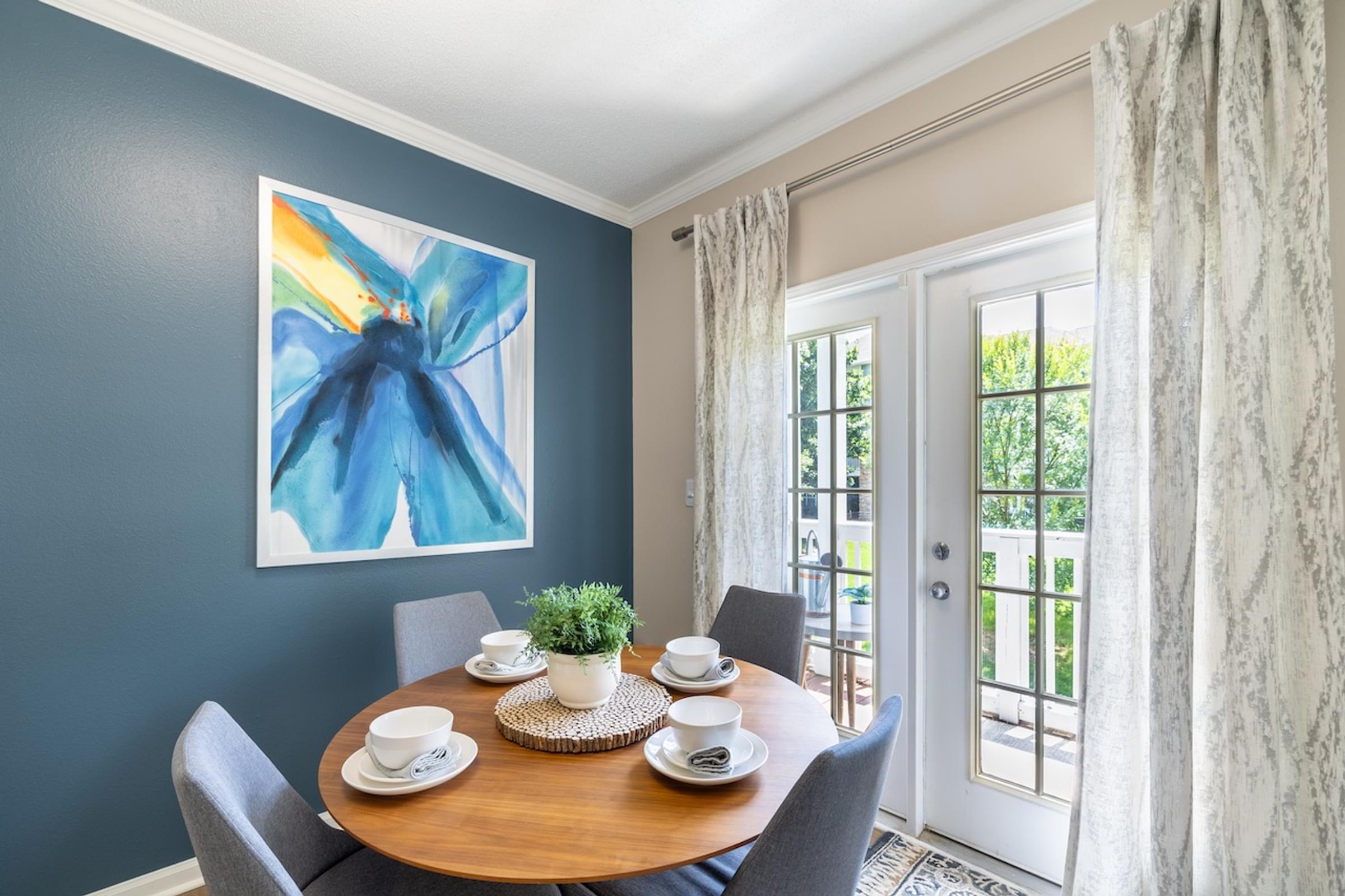 a dining room with a table and chairs and a door to a balcony