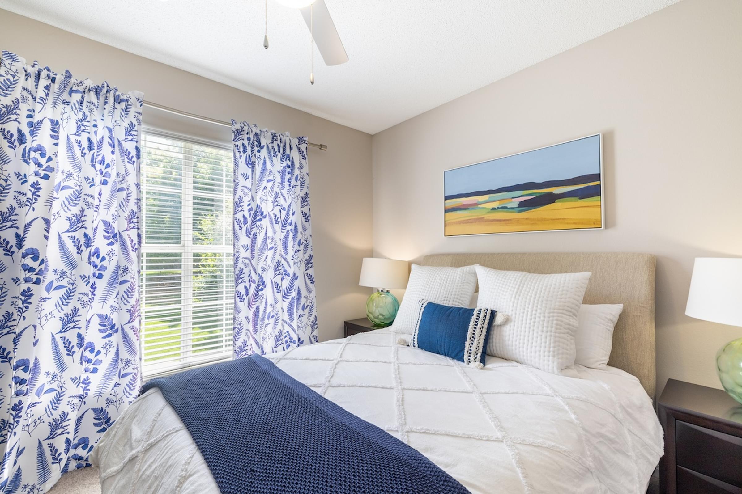a bedroom with a bed and a window with blue and white curtains