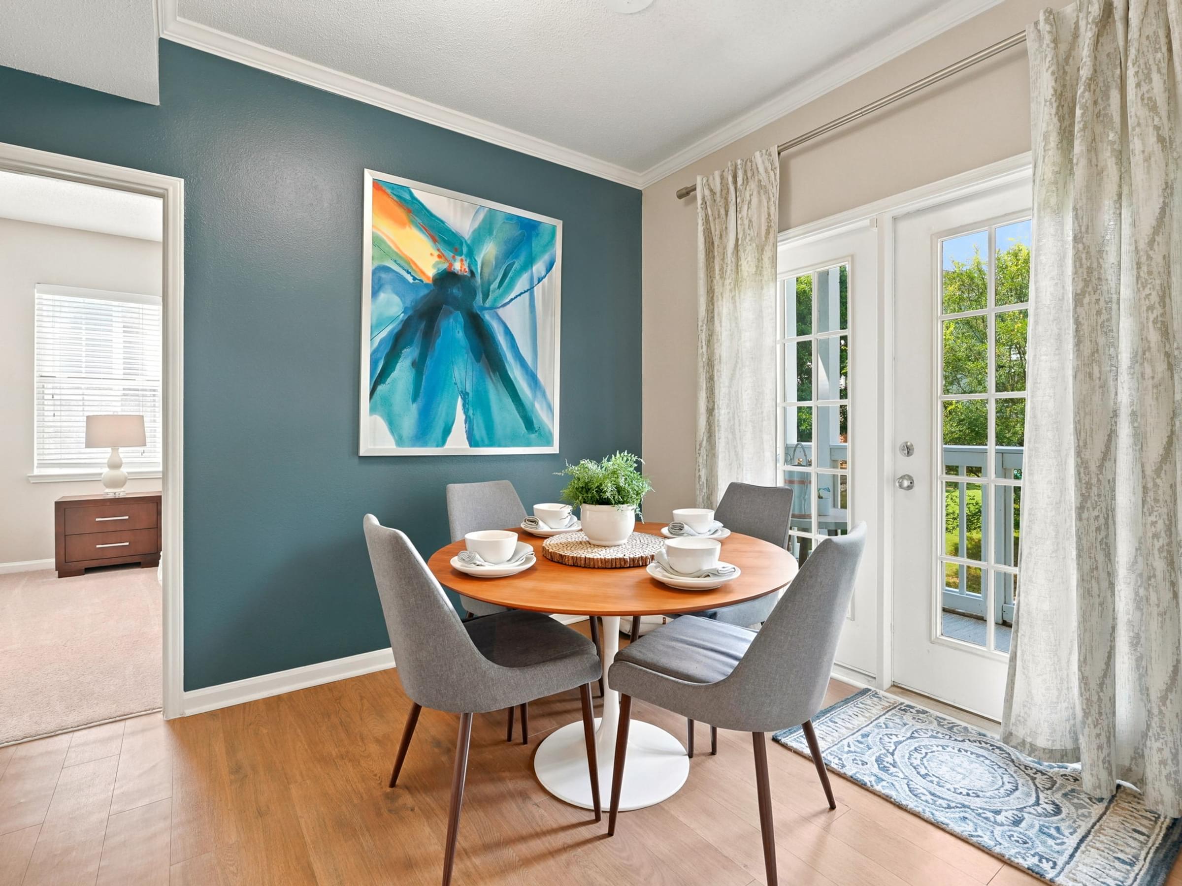 A dining room with a table set for two and a painting on the wall.