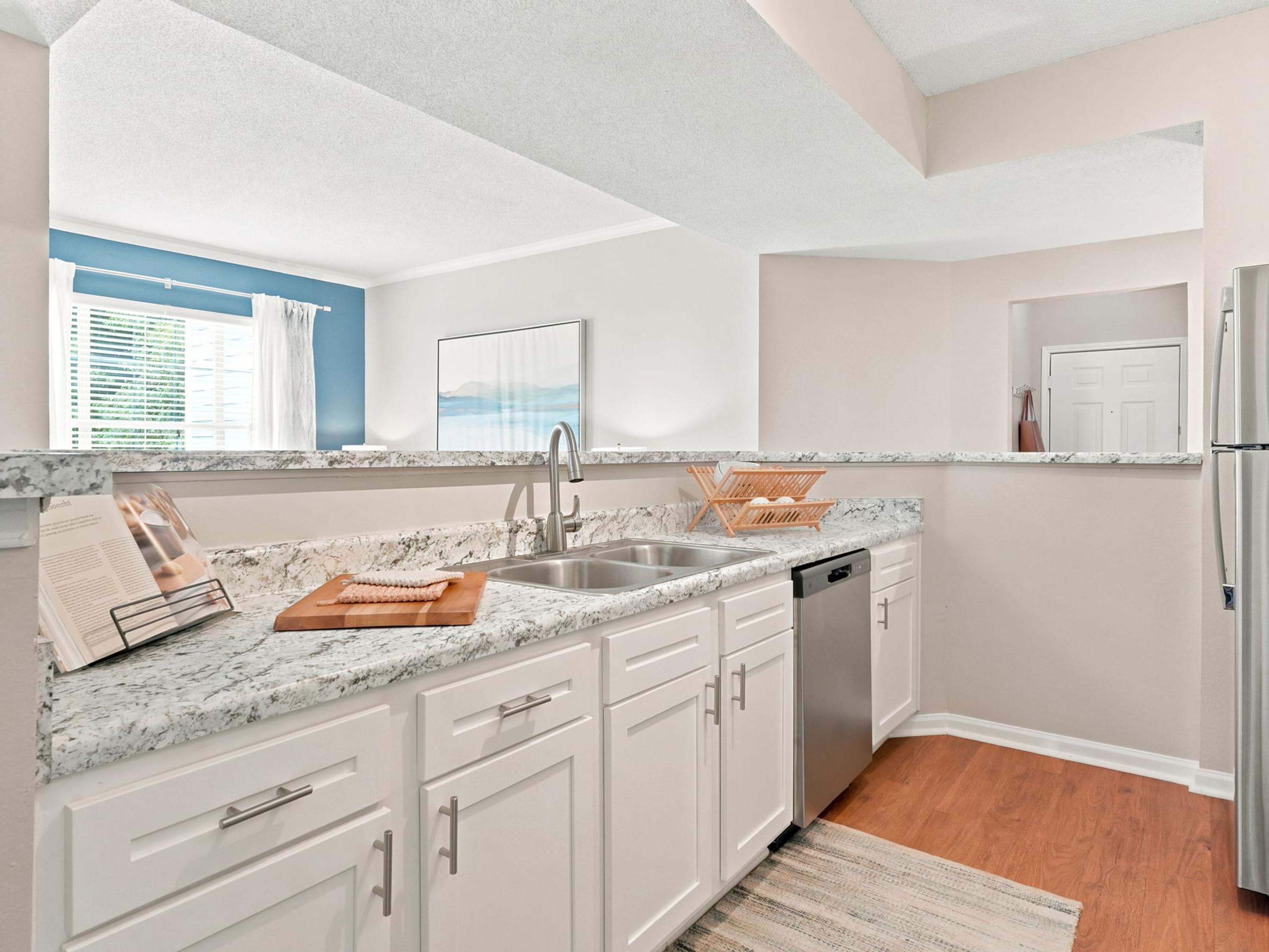 A kitchen with white cabinets and a marble countertop.