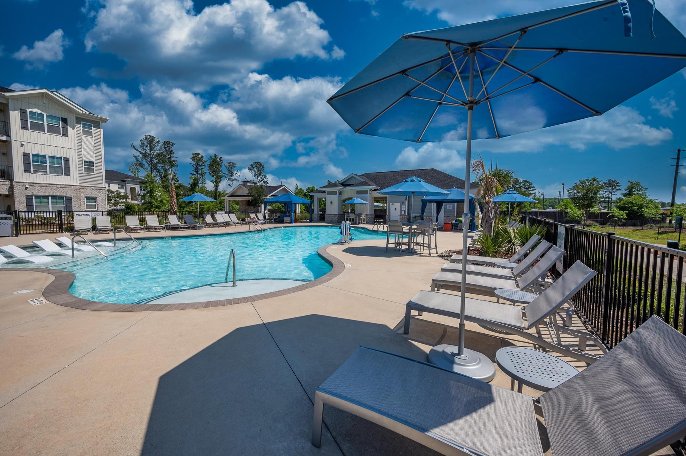 A large blue umbrella is on a patio next to a pool.