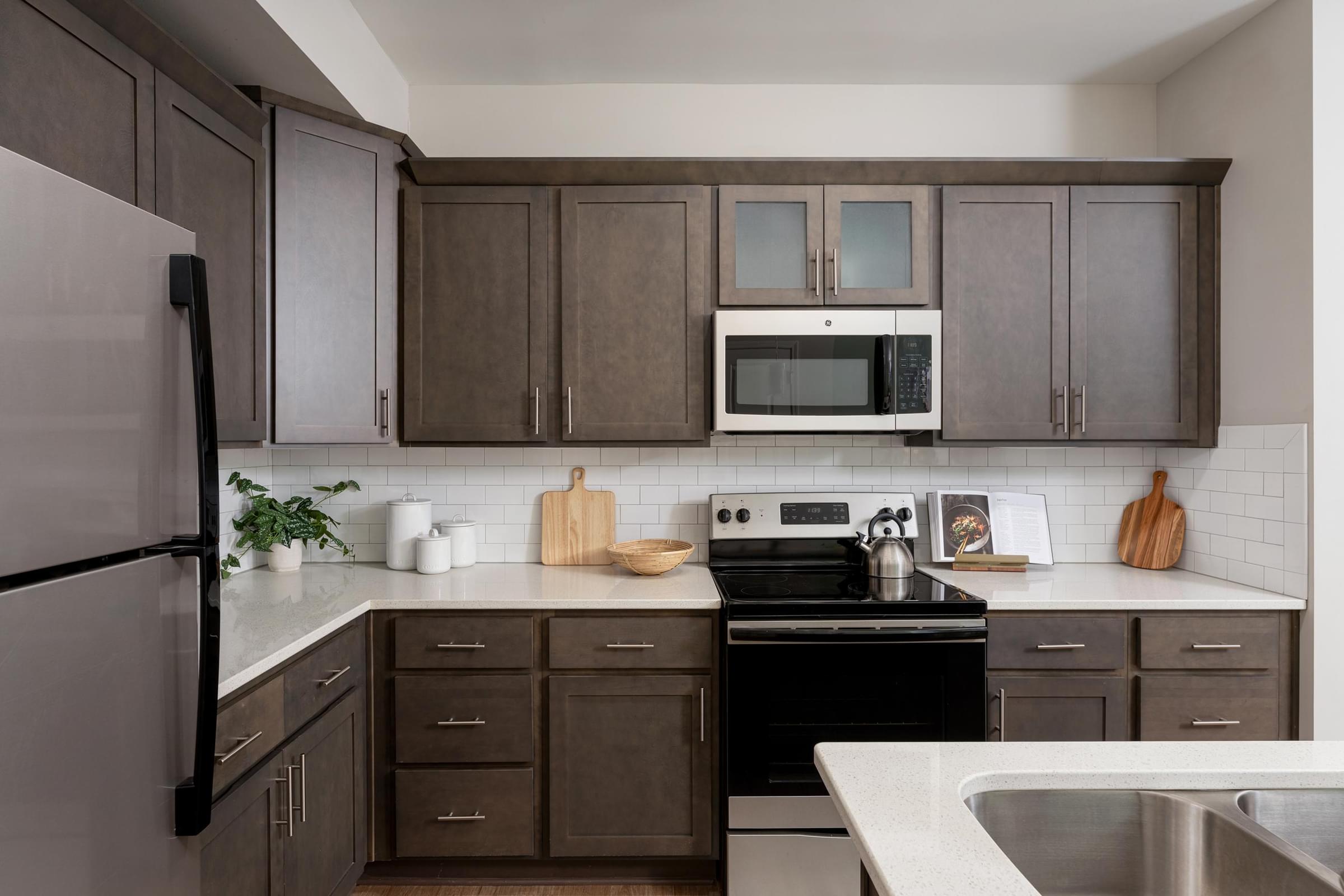 A kitchen with brown cabinets and a black refrigerator.