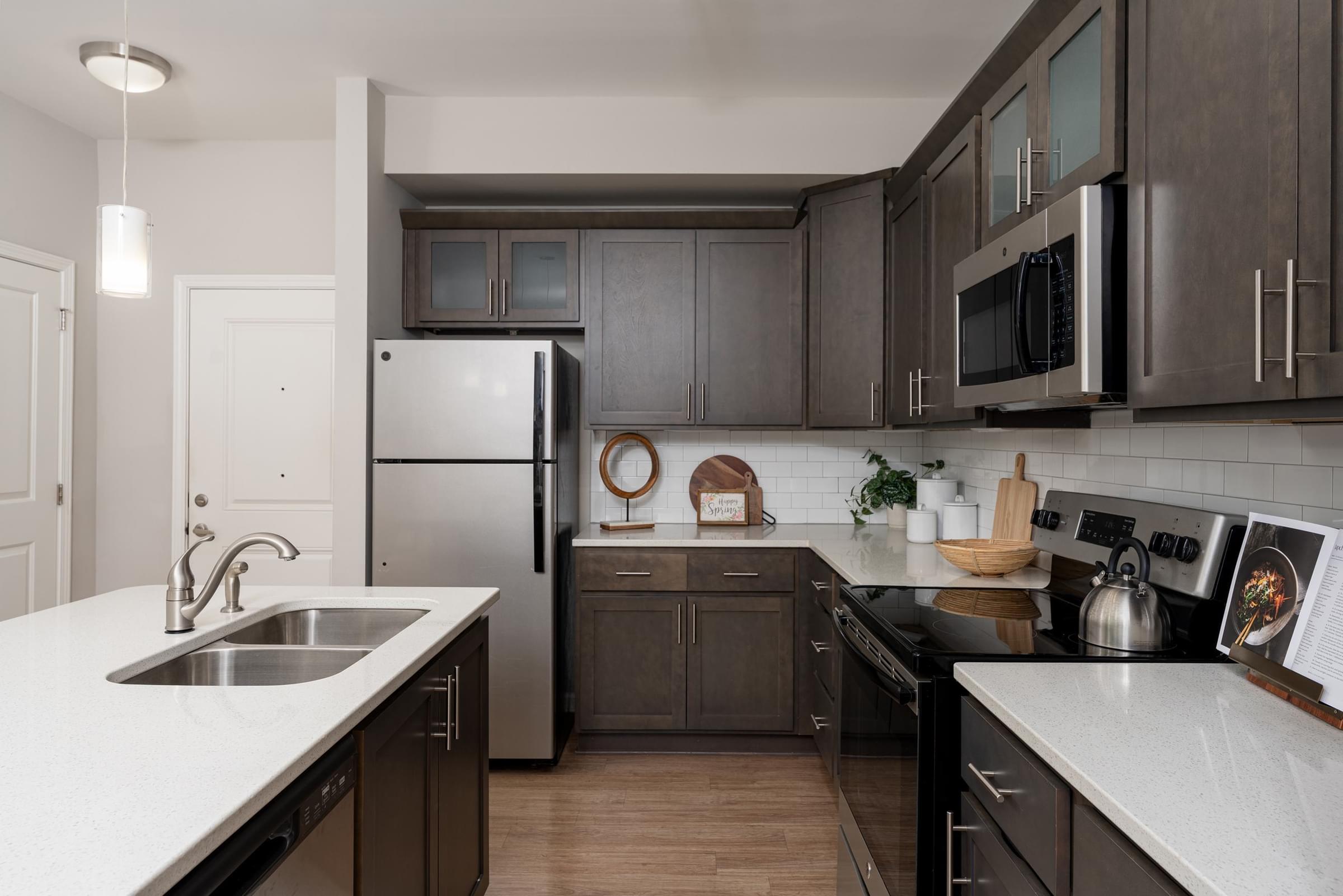 A modern kitchen with dark wood cabinets and stainless steel appliances.