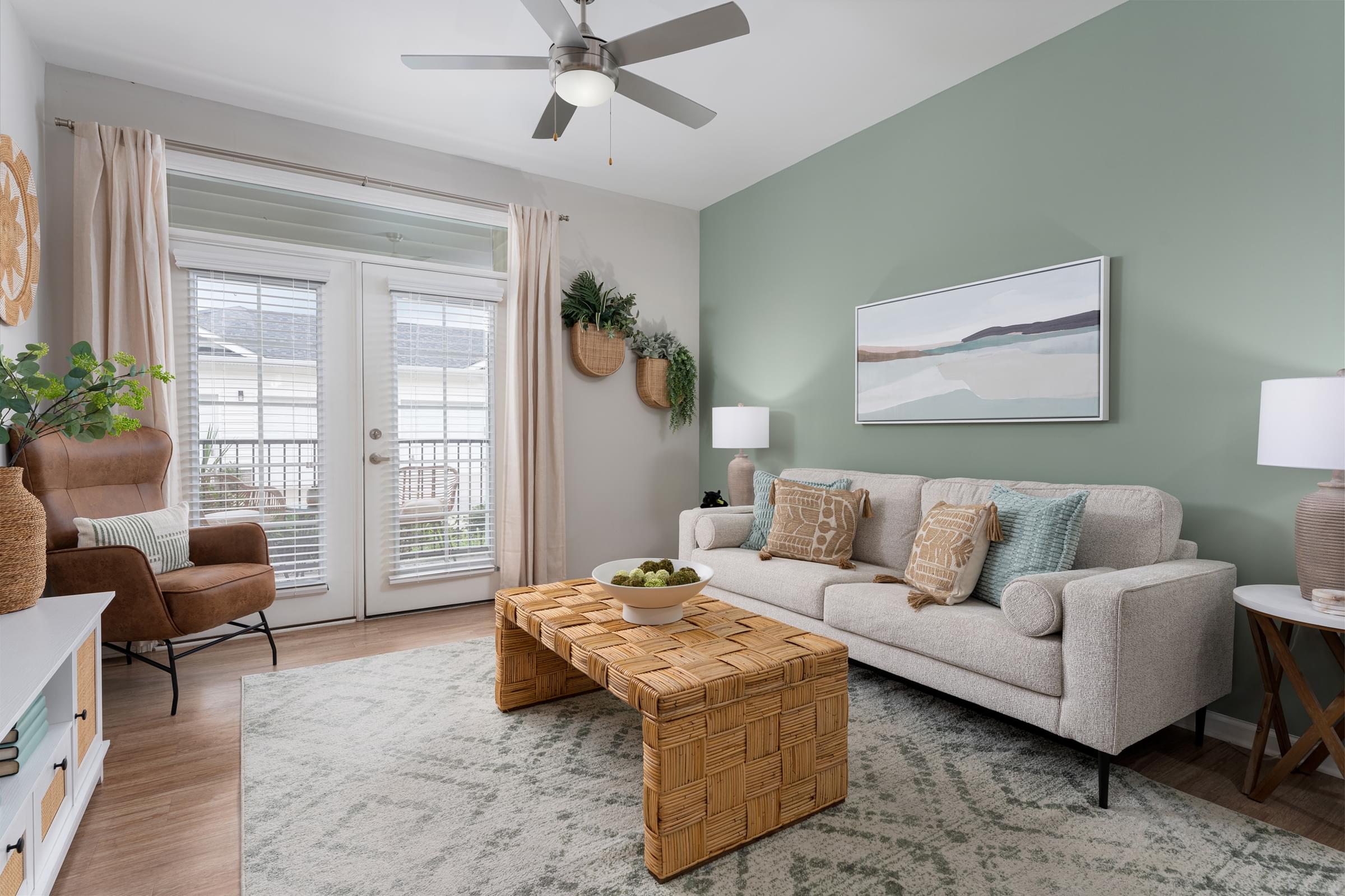 A living room with a couch, a chair, a coffee table, and a ceiling fan.