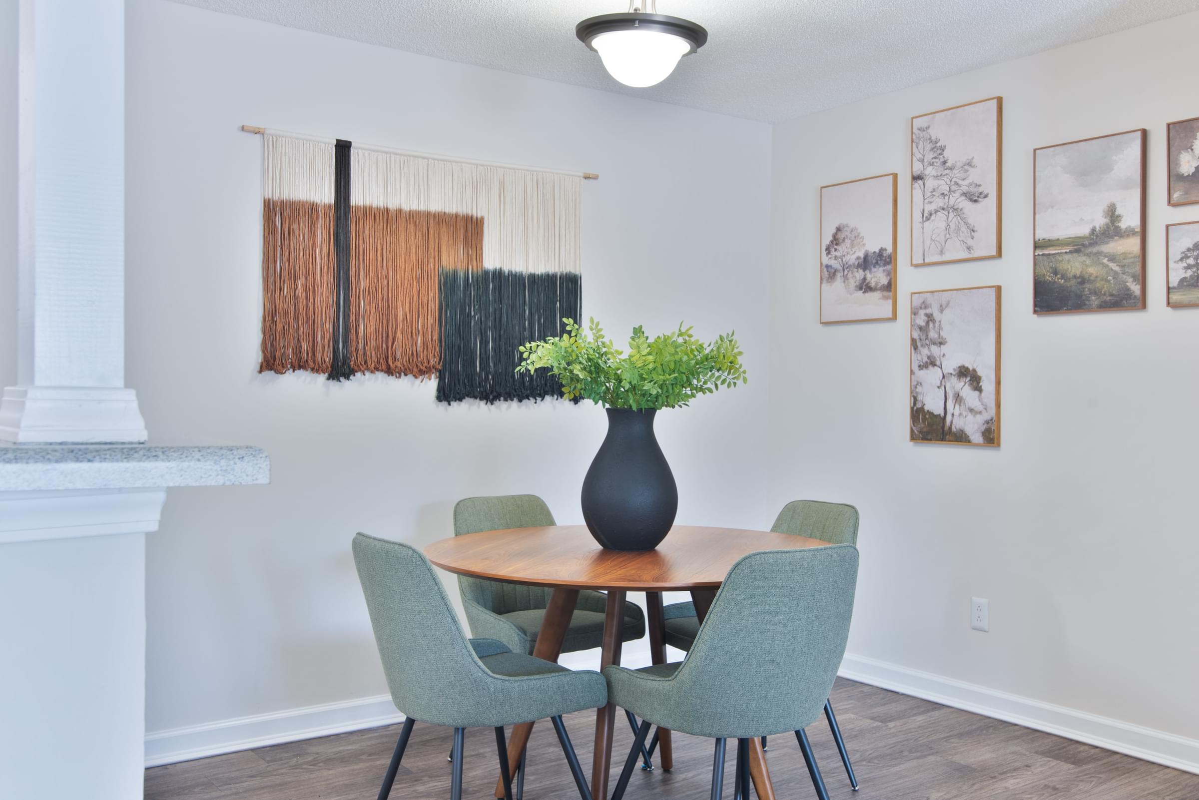 A dining room with a table, chairs and pictures on the wall.