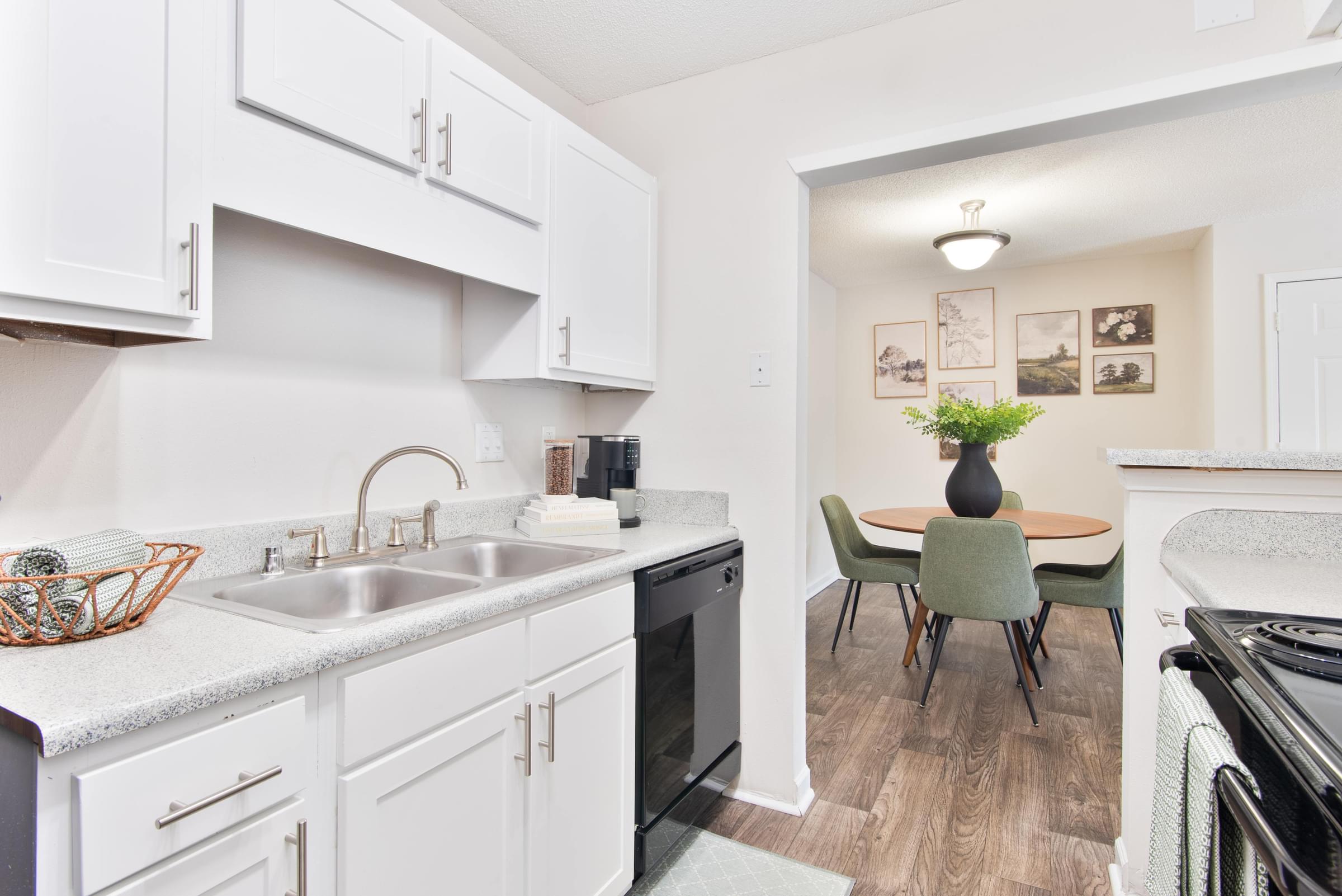 A kitchen with white cabinets and a green chair.