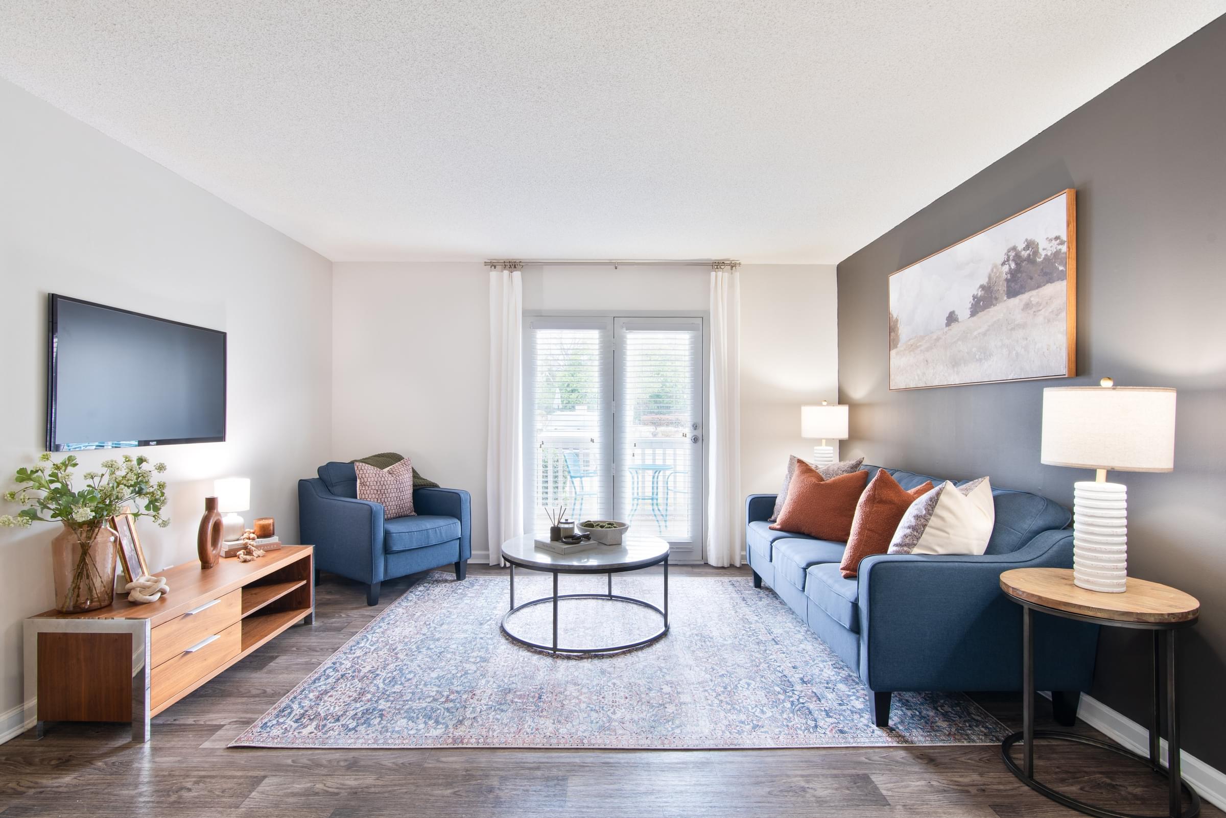A living room with a blue couch and a television on the wall.